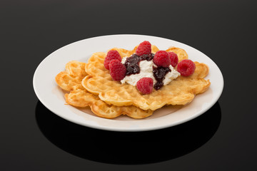 waffle with cream, jam and raspberries on dark background.