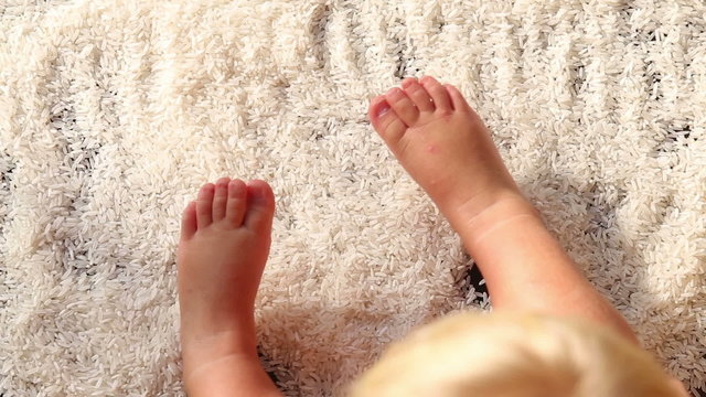 baby legs tread over white rice surface	