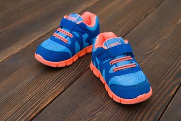 pair of blue sporty shoes for kid on wood