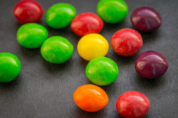 Colorful chewy dragees on a dark background.