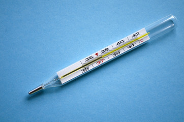 Mercury thermometer shows subfebrile temperature on a blue backg