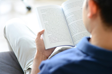 Fototapeta premium A man reading book while sitting on the couch
