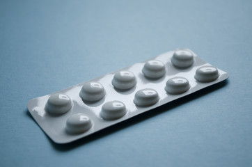 Ten pills in blister pack close-up on blue background