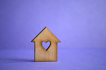 Obraz na płótnie Canvas Wooden house with a hole in the form of heart on a purple backgr