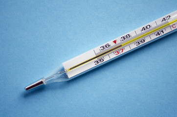 Mercury thermometer shows subfebrile temperature on a blue backg