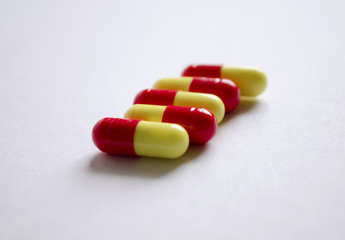 Five red and yellow capsules on a light background
