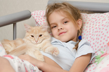 Portrait of the girl with a cat lying in bed