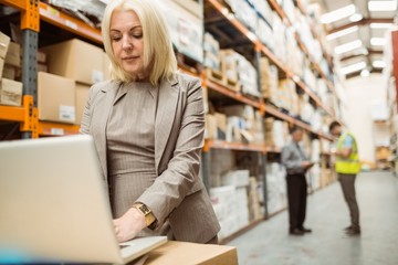 Focused warehouse manager working on laptop