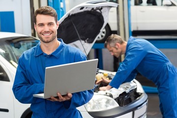 Smiling mechanic using a laptop
