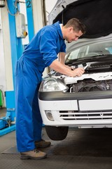 Mechanic examining under hood of car