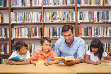 Cute pupils and teacher reading in library