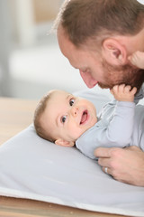 Fototapeta premium Daddy cuddling baby boy on changing table