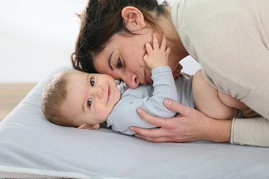 Mommy cuddling baby boy on changing table