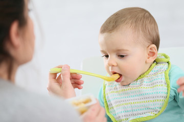 Mother giving fruit sauce to baby boy