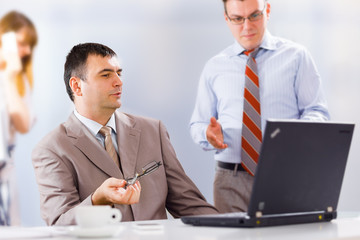 Businesspeople working on laptop in an office