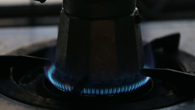 man hand set gas fire at the gas-stove with coffee-pot stand on 