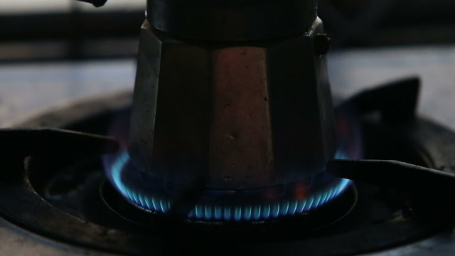 man hand set gas fire at the gas-stove with coffee-pot stand on 
