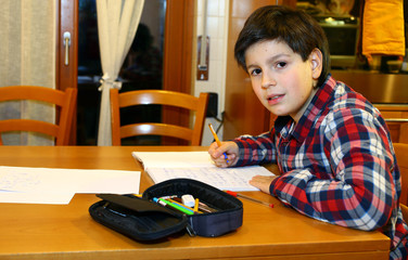 young boy writes on his notebook at home 5