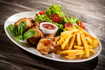 Grilled chicken legs with chips and vegetables
