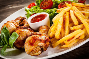 Grilled chicken legs with chips and vegetables