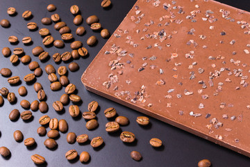 Coffee beans and dark chocolate on black background