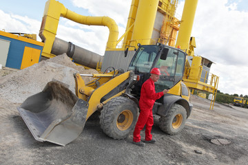 worker in red uniform on phone at buldozer