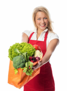 Frau mit Schürze hält Tasche mit Gemüse