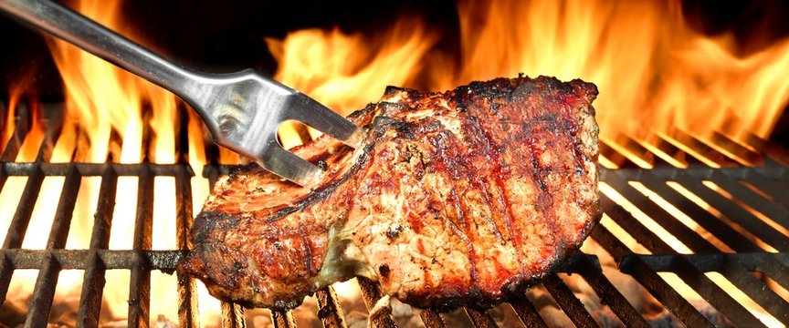 Grilled Pork Chop on Flaming BBQ Grill.
