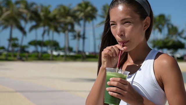 Healthy woman drinking green vegetable smoothie