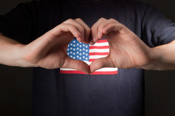 man with american flag on shirt showing heart of his hands