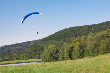Blue paraglider flying in beatiful nature