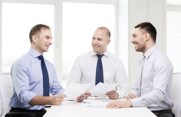smiling businessmen with papers in office