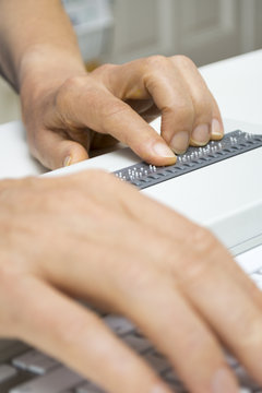 Blind person reads on braille display from computer screen