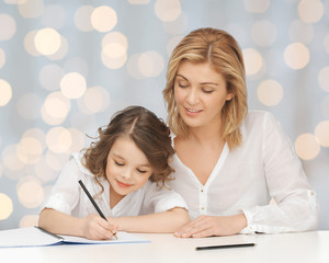 happy mother and daughter writing in notebook