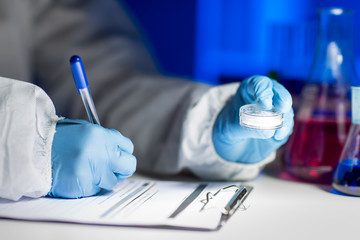 close up of scientist writing test results in lab