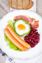 Egg fried in a green pepper, sausages, bacon and red beans
