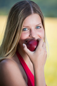 Beautiful smiling young woman and bit red apple
