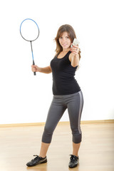 Young woman holding racket and shuttlecock playing badminton