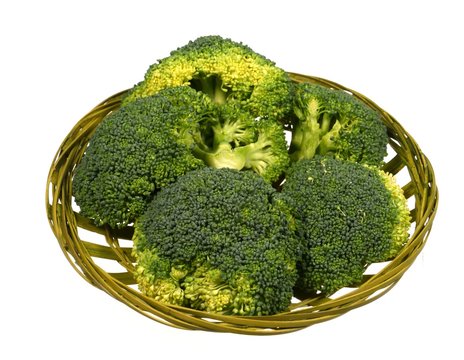 Fresh broccoli in a green basket over white