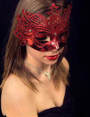 Beautiful girl in a carnival mask on a black background - obrazy, fototapety, plakaty