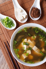 miso soup in a white bowl and ingredients vertical top view