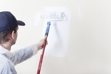 Maler streicht Wand mit Farbrolle weiss - 76853433