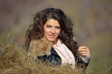 Beautiful young woman relaxing under a hay stack in autumn