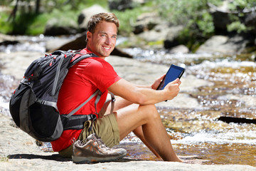 Tablet hiking man reading ebook or map in nature