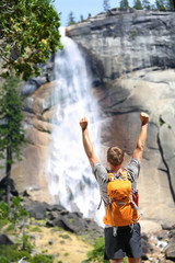 Obraz premium Happy hiking man cheering in success by waterfall