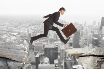 Businessman jumping over rocks