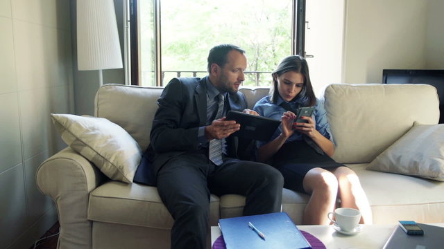 business people with tablet computer and smartphone on sofa