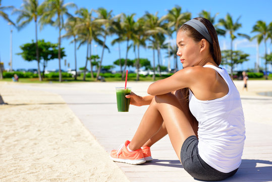 Healthy woman runner drinking green smoothie