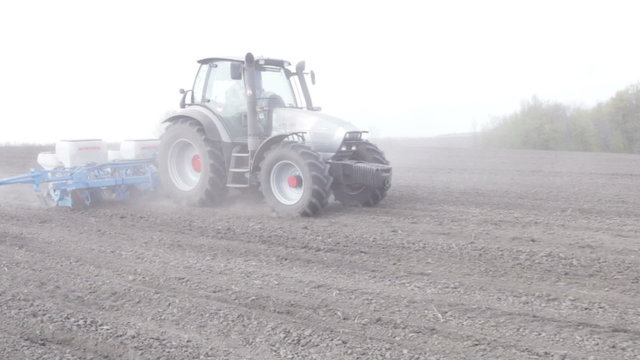Tractor with planter sows black boundless field clouseup