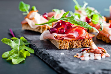 Sliced prosciutto with herbs and pomegranate seeds